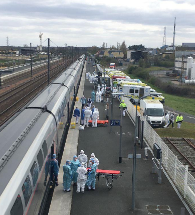 Andana de l'estació de Poitiers en la descàrrega d'un TGV sanitari Chardon. Un parell de lliteres envoltades de personal sanitari amb protecció contra la COVID esperen la sortida de pacients del tren per portar-los a les ambulàncies que els esperen, aparcades de cul, a l'altra costat de l'andana