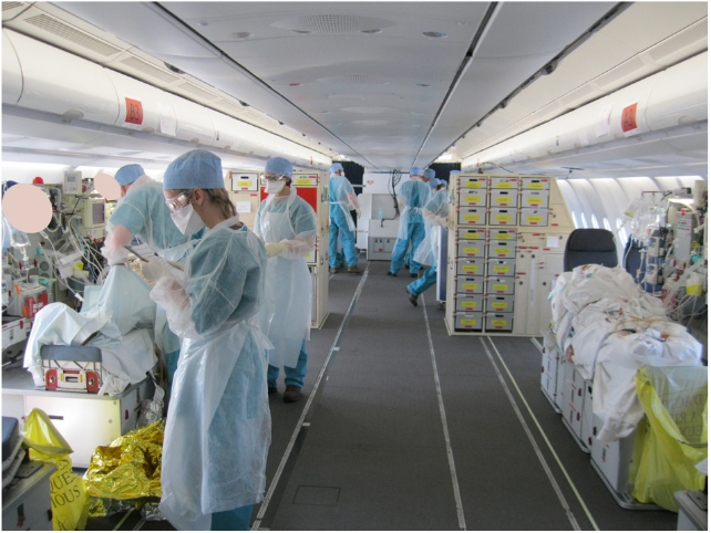 Interior d'un avió de passatgers modificat per a poder traslladar pacients amb COVID. Es veuen diverses lliteres amb pacients i equipament mèdic. Una colla de sanitaris amb els EPI COVID es mouen per dins l'aeronau.